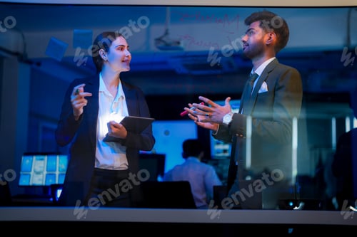 Preview: A businesswoman and a businessman writing ideas on a glass wall with colorful markers. The woman hol