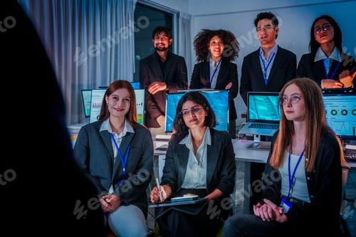 Preview: Large multiethnic startup team looking at a leader during a late night meeting. Professional men and