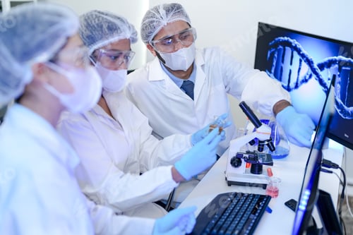 Preview: A focused scientist in protective gear using a microscope to analyze genetic samples with a digital
