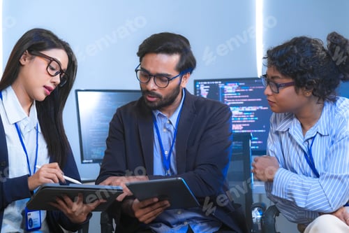 Preview: A team of IT professionals typing at their computers in the office row, working along a row of compu