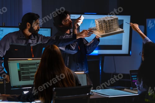 Preview: Construction project team reviews architectural plans and a scale building model in a dark operation