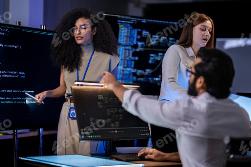 Preview: Red-haired female in a cream jacket points at a document while a Black female analyst looks on in a