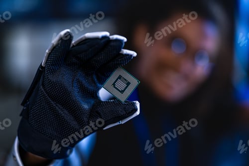 Preview: A gloved hand carefully holds a CPU chip in a dark cybersecurity lab environment; blue monitoring sc