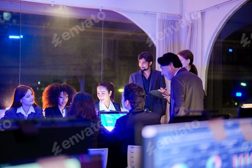 Preview: Diverse group of business professionals engaged in an active team discussion and meeting at night. F