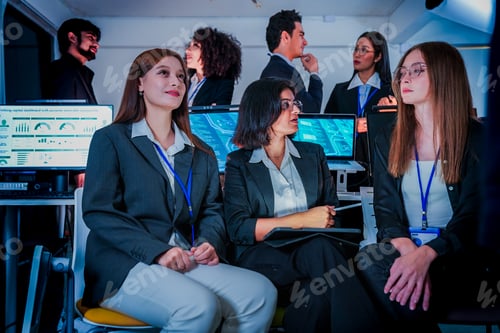 Preview: Large multiethnic startup team looking at a leader during a late night meeting. Professional men and