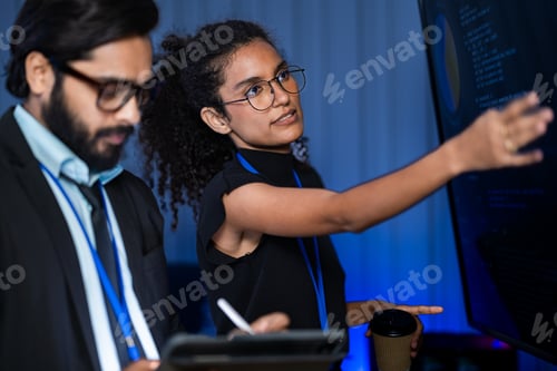 Preview: South Asian male IT security engineer and Black female researcher with a white robotic arm examine s
