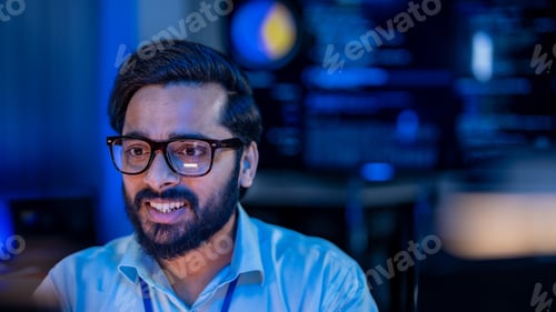 Preview: Focused Indian technology professional pointing at an office computer monitor to debug core processo