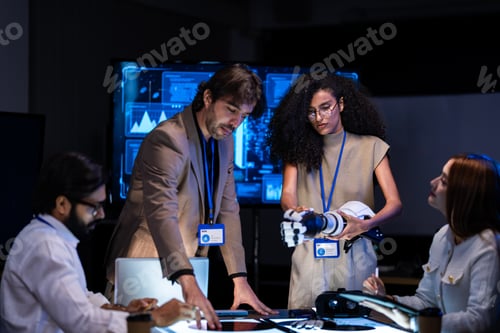 Preview: Male presenter in a tan blazer stands before large glowing blue AI car visualization screens in a da