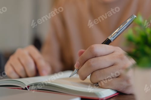 Preview: man hand writing in notebook with pen. Student studying or business person taking notes on paper at