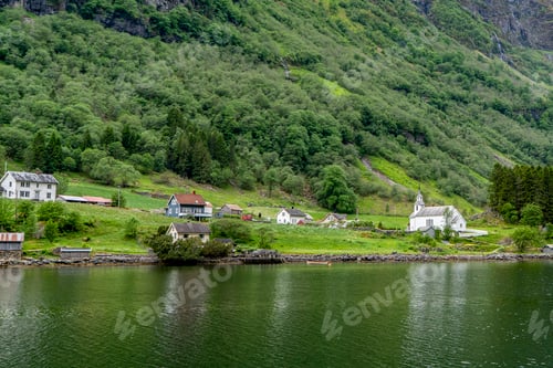 Preview: Rural houses reflected in a calm fjord's green water