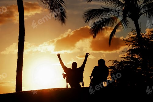 Preview: Silhouettes of people watching the sunset from beach chairs in Maui, Hawaii, USA