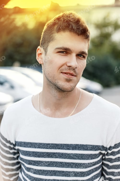Preview: Handsome stylish man with a beard wearing a sweater at sunset.
