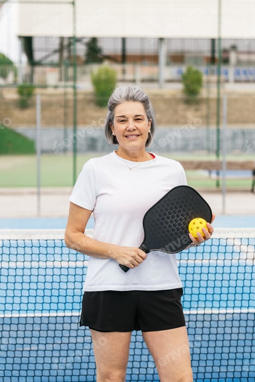 Preview: Senior woman playing pickleball smiling on court