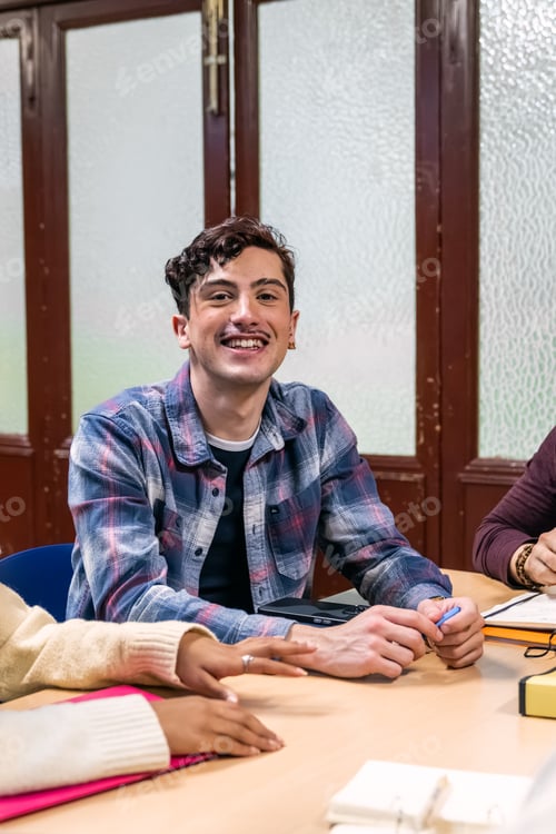 Preview: Smiling young man studying in a classroom or library