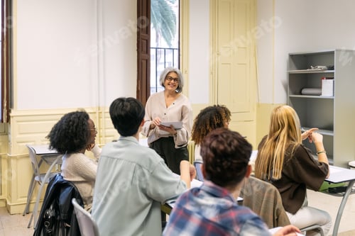 Preview: Mature teacher discussing with diverse students in classroom