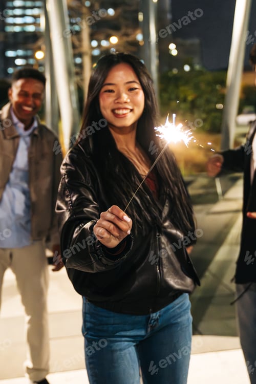 Preview: Multiethnic friends having fun celebrating with sparkler at night