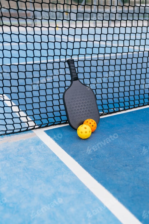 Preview: Pickleball paddle and balls resting on court