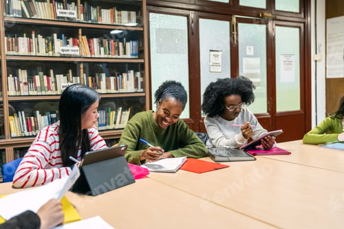 Preview: Diverse students studying together in library using technology