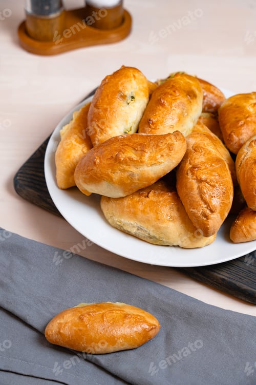 Preview: Plate Of Golden Baked Bread Rolls On Table