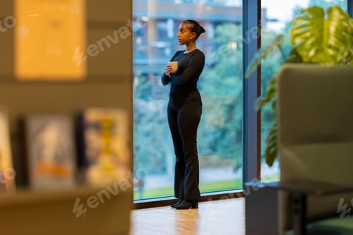 Preview: Woman enjoys coffee by large window
