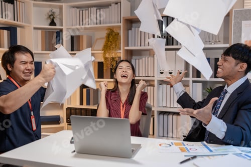 Preview: Business team celebrating success in office, throwing documents in the air with joy, expressing achi