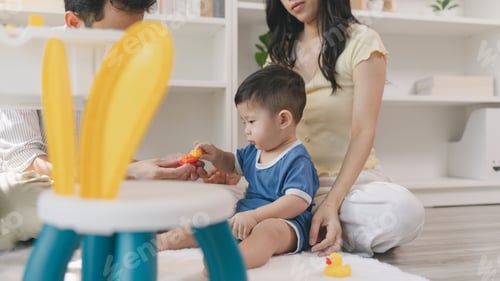 Preview: Young Toddler Playing With Plastic Blocks On Floor With Parents
