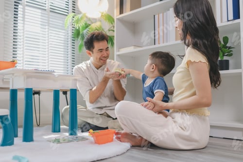Preview: Young parents playing with baby using colorful toys at home, encouraging learning and motor skills,
