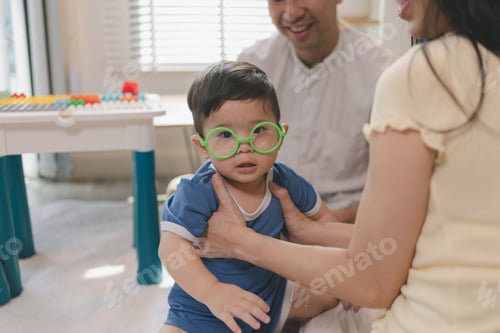 Preview: Toddler Boy Wearing Bright Green Toy Glasses Playing with Parents
