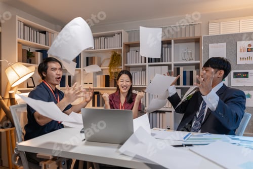 Preview: Business team celebrating success in office, throwing papers into the air with joy, showing achievem