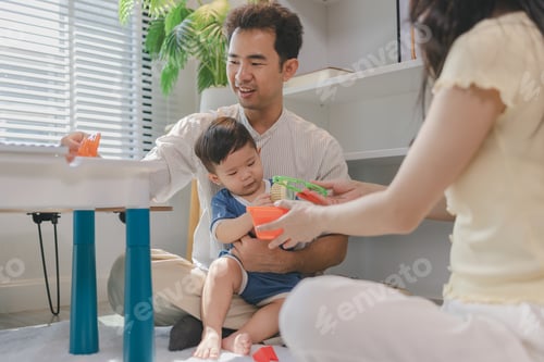 Preview: Young parents playing with baby using colorful toys at home, encouraging learning and motor skills,