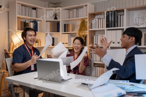 Preview: Business team celebrating success in office, throwing documents in the air with joy, expressing achi