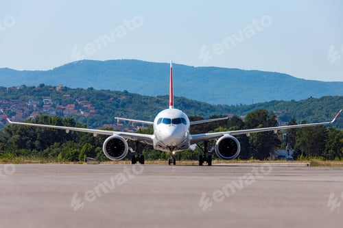 Preview: Airplane on runway at airport preparing for takeoff with mountains in the background