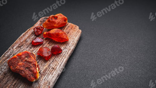 Preview: Natural amber. A piece of yellow transparent natural amber on large piece of dark stoned wood.