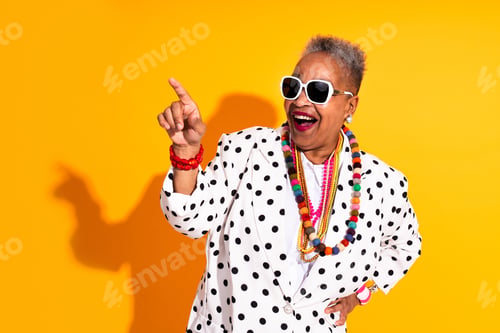 Preview: Joyful senior woman pointing to copy space