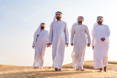 Preview: Arab friends bonding walking in desert wearing kandura