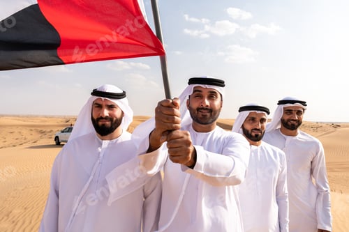Preview: Emirati men holding uae flag in desert celebrating national day