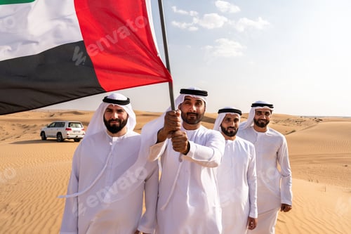 Preview: Emirati men holding united arab emirates flag in desert