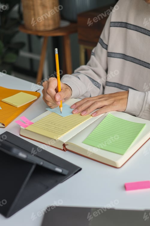 Preview: Young man taking notes while watching online course or webinar.