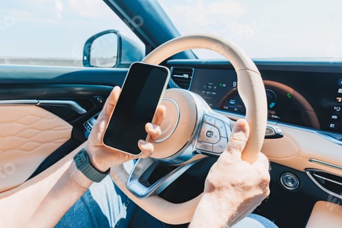 Preview: Smartphone held in hands while driving luxury car interior with elegant dashboard details