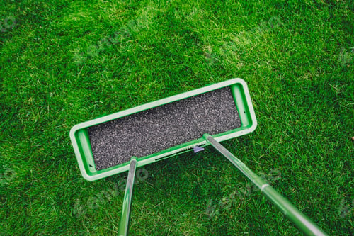 Preview: Green lawn roller applying a smooth layer of gravel on freshly cut grass surface