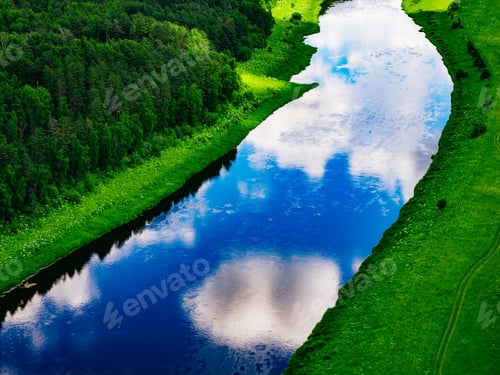 Preview: Curved river reflecting clouds and greenery along the water's edge under bright daylight conditions