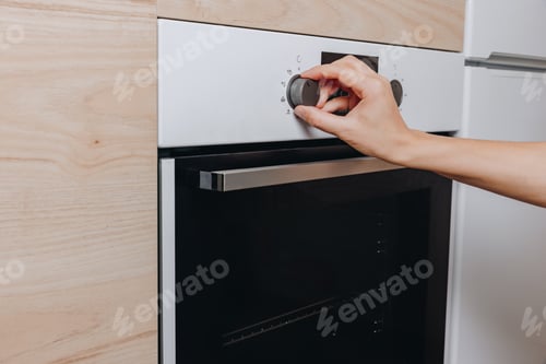 Preview: Close Up of Hand Adjusting Control Dial on Modern Oven