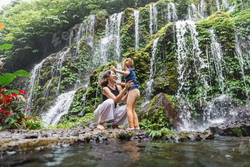 Preview: Happy mother and daughter hugging near waterfall in Bali