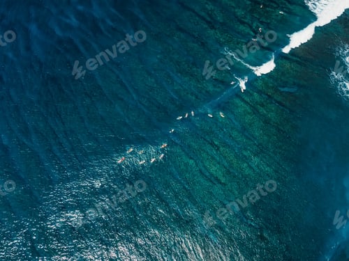 Preview: Drone shot of surfers riding waves over coral reef in Bali, tropical surf trip