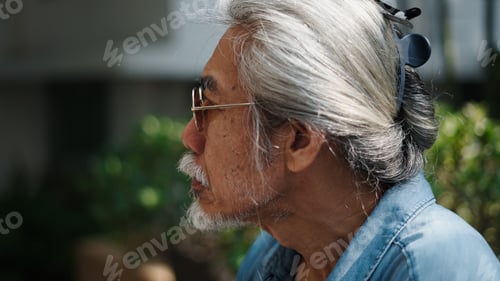 Preview: Senior asian man with grey hair and beard looking out, reflecting thoughts