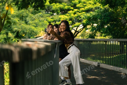 Preview: Happy young asian women friends taking selfie outdoors on a sunny day