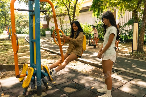 Preview: Young women exercising outdoors on elliptical machine at public park