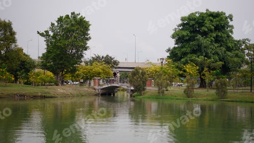 Preview: Couple standing on stone bridge enjoying serene park view with tranquil water