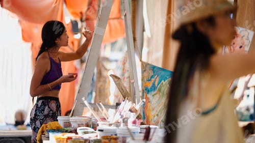 Preview: Young woman artist expressing creativity by painting on a canvas outdoors