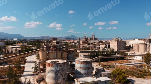 Preview: Abandoned industrial complex with old silos and buildings under a clear blue sky